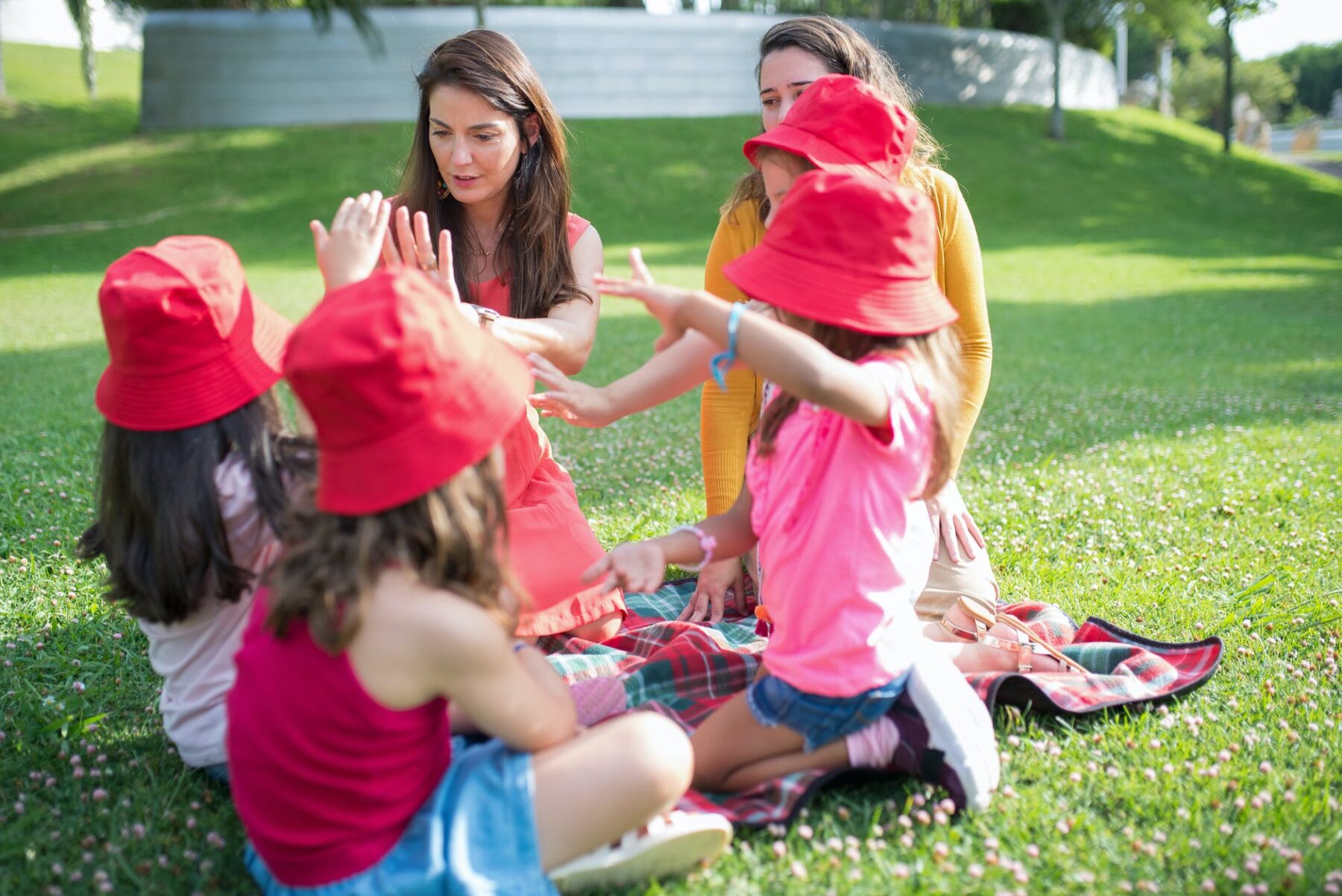 girls in red hat sitting on green grass field